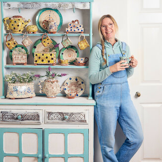 Sarah Monk standing by her ceramics in her studio at Eastnor Pottery.